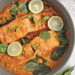 Juicy baked salmon in a tomato sauce with basil and lemon slices.