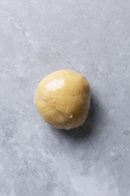 Softened butter wrapped in plastic on gray surface, ready for baking or cooking.