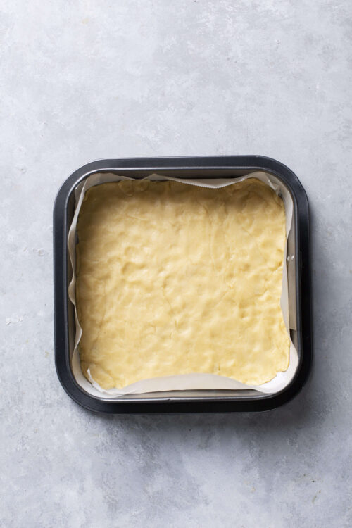 Golden homemade pie crust in a baking pan ready for filling.