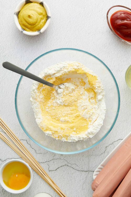 Flour, eggs, and ingredients for baking pasta dough on white surface.