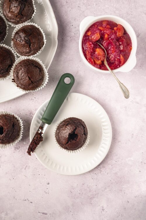 Rich chocolate muffins with cracked tops served on white plates.