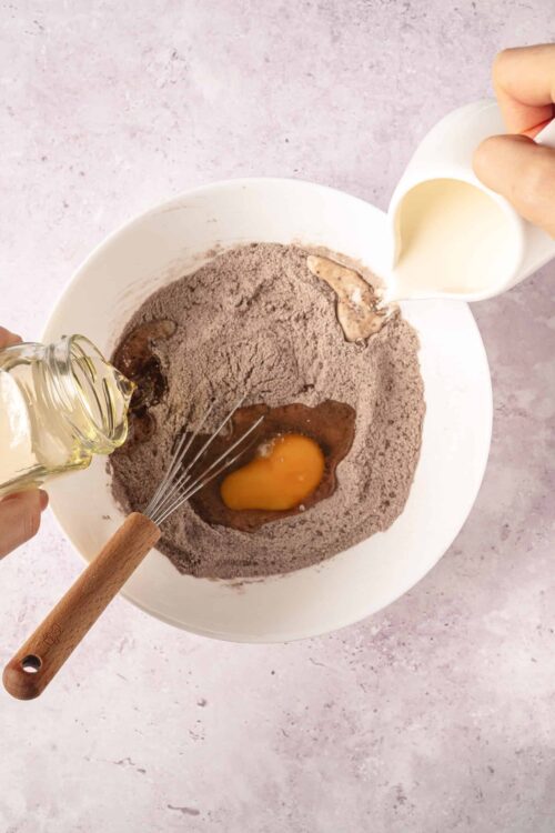 Flour and ingredients being combined for baking, with eggs and milk in a mixing bowl.