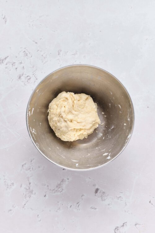 Buttery pie dough in a steel mixing bowl for baking recipes.