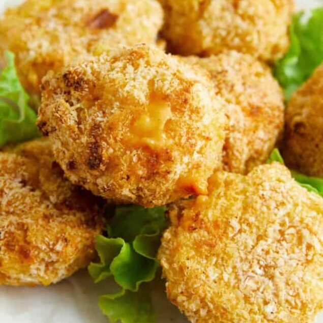 Golden crispy baked chicken nuggets on a white plate with lettuce.