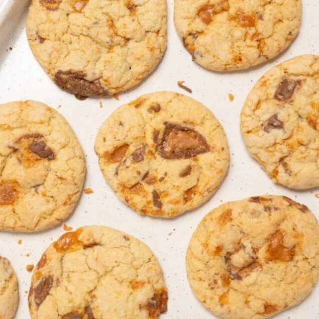 Buttery chocolate chip cookies with caramel bits on baking sheet.