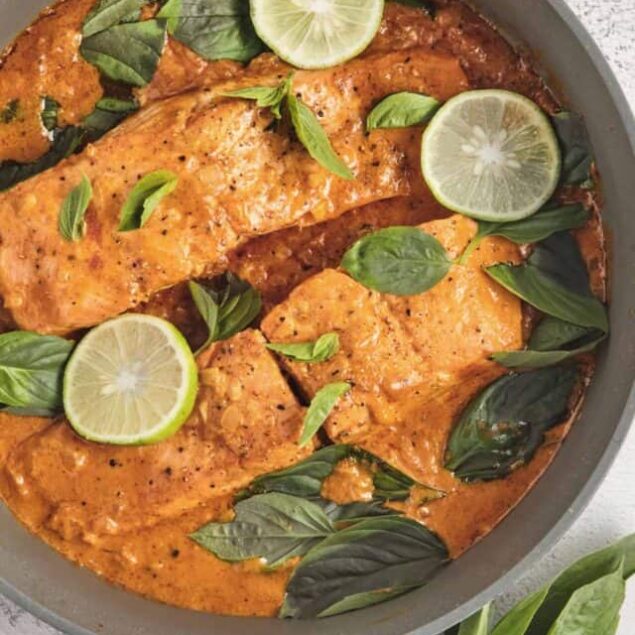 Juicy baked salmon in a tomato sauce with basil and lemon slices.