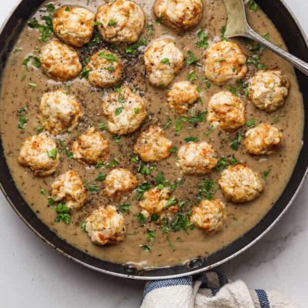 Savory chicken meatballs in creamy mushroom sauce in a cast iron skillet.