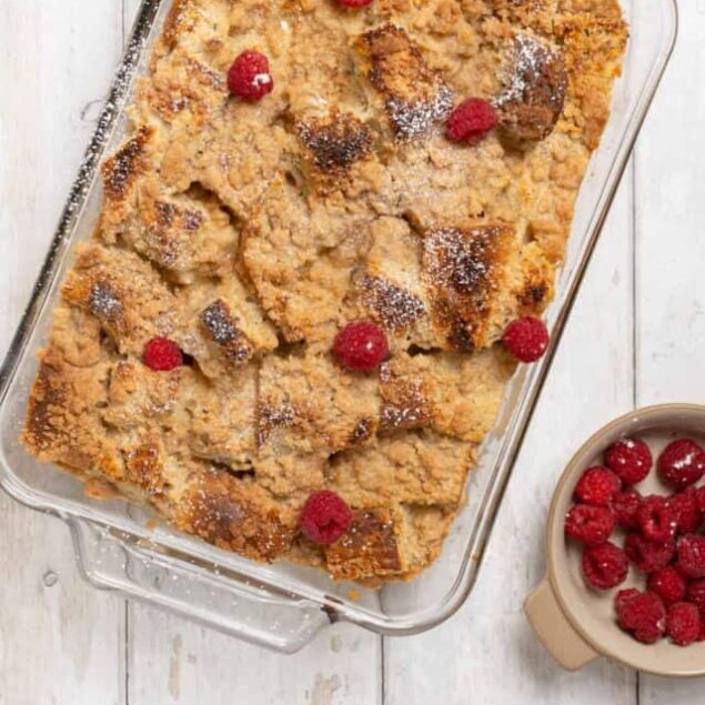 Butterscotch crumble dessert with raspberries in a glass baking dish.