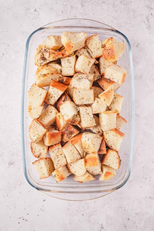 Cubes of toasted bread with seeds in a glass baking dish.