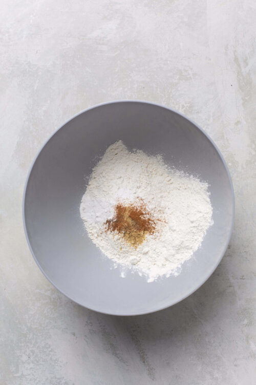 Flour and spices in a gray mixing bowl for baking recipes.