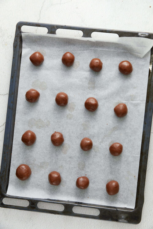 Chocolate cookie dough balls on baking tray for baking or cookies.