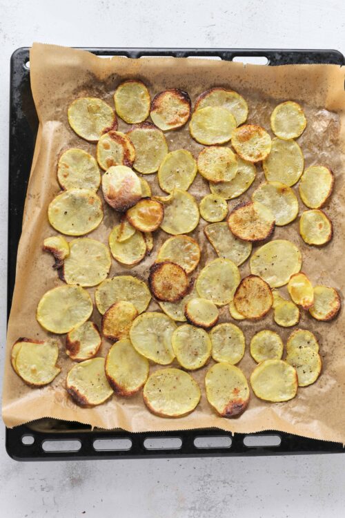 Golden roasted potato slices on a baking sheet.