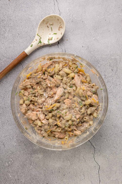 Creamy tuna pasta salad in a clear glass bowl, ready to serve, topped with fresh herbs.