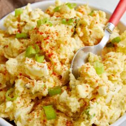 Buttery mashed potatoes with green onions and paprika, served in a white bowl. Perfect comfort food for any occasion.