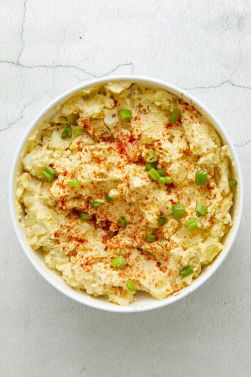 Creamy potato salad with chopped green onions and paprika sprinkle.