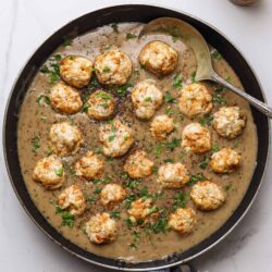 Savory chicken meatballs in creamy mushroom sauce in a cast iron skillet.