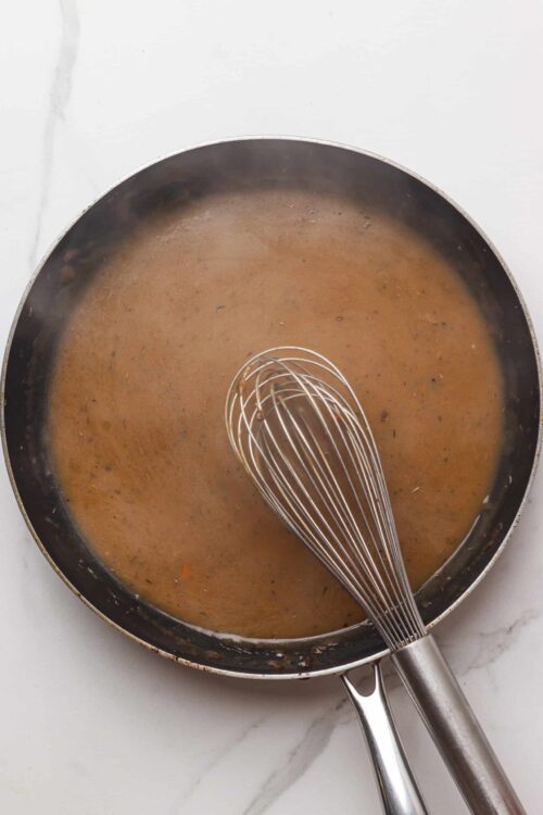 Smooth caramel sauce in a frying pan with a whisk.