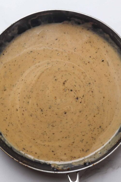 Creamy seasoned gravy in a skillet, ready for serving or use in savory recipes.