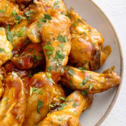 Crispy buffalo chicken wings with parsley garnish, close-up shot, baked Bree.