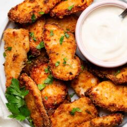 Crunchy baked chicken wings with a side of creamy dipping sauce. Perfect for snack or game day appetizers. Garnished with fresh herbs.