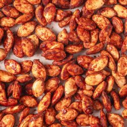 Roasted spiced pumpkin seeds on baking sheet.