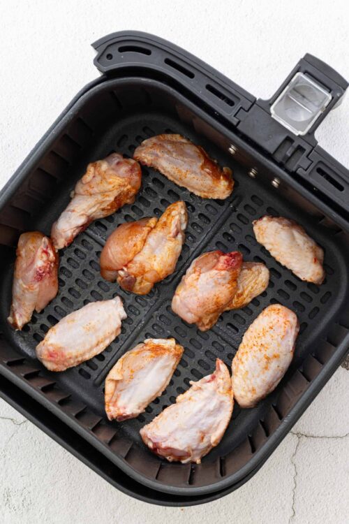 Juicy seasoned chicken wings in an air fryer ready to cook.