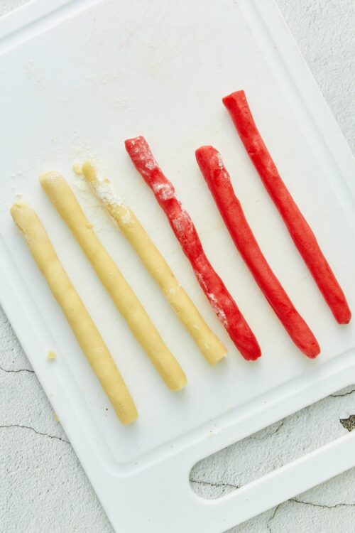 Colorful colorful homemade breadsticks on a white cutting board.