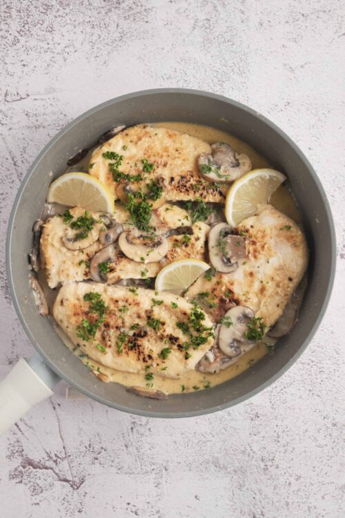 Juicy baked chicken with lemon, mushrooms, and fresh herbs in a creamy sauce.