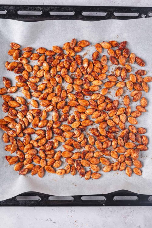 Roasted spiced pumpkin seeds on baking sheet.