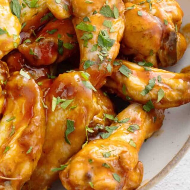 Crispy buffalo chicken wings with parsley garnish, close-up shot, baked Bree.