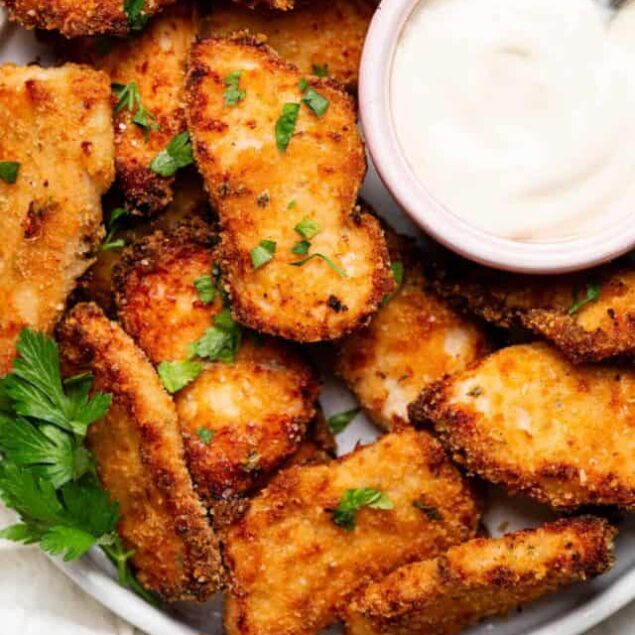 Crunchy baked chicken wings with a side of creamy dipping sauce. Perfect for snack or game day appetizers. Garnished with fresh herbs.