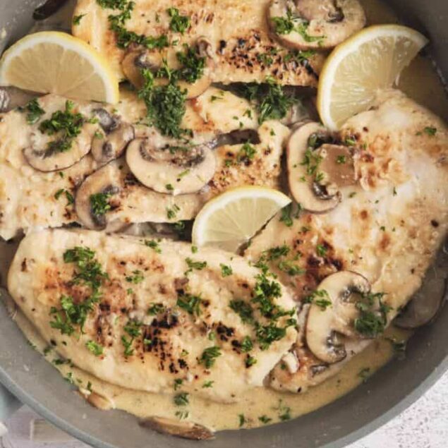 Juicy baked chicken with mushrooms, lemon slices, and fresh herbs in a creamy sauce.