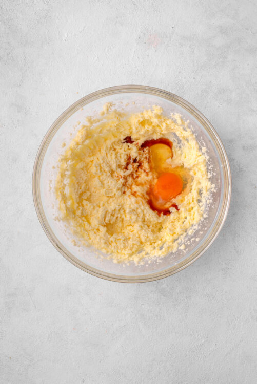 Creamy butter and sugar mixture with eggs in a glass bowl for baking recipes.