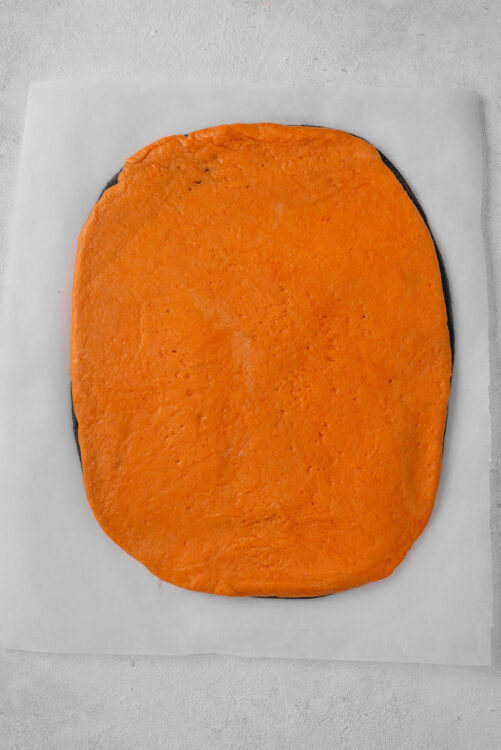 Sweet potato layer cake with bright orange frosting on baking sheet.