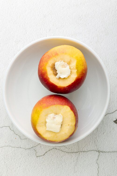 Juicy baked apples with butter and cinnamon on a white plate.