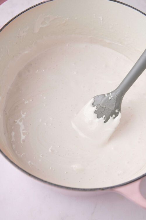 Creamy pancake batter in a pink mixing bowl with a silicone spatula, ready for cooking.