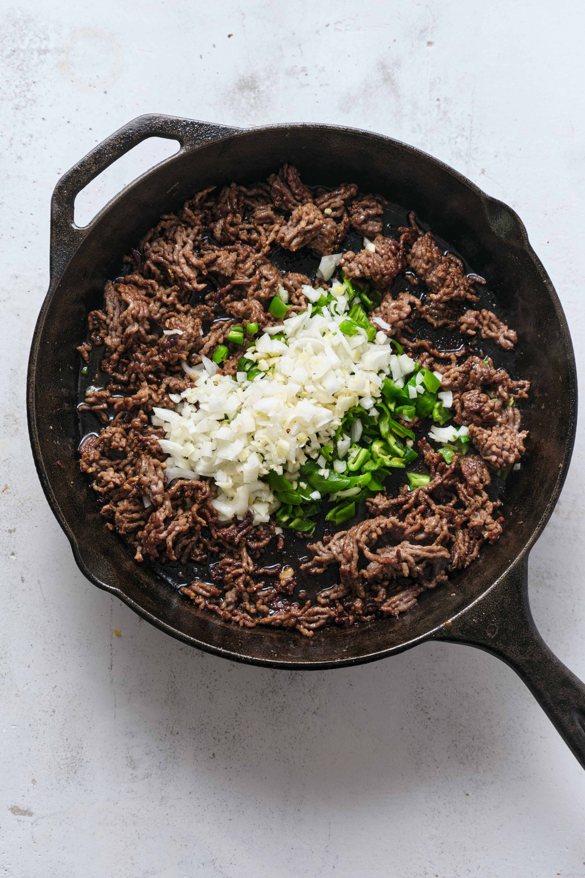 Ground beef cooking with onions and green onions in cast iron skillet for easy meal prep.
