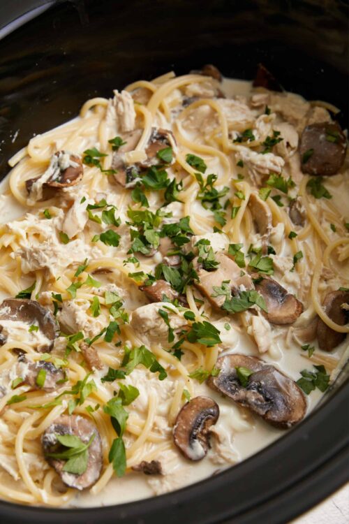 Creamy mushroom chicken pasta in slow cooker with fresh parsley garnish.