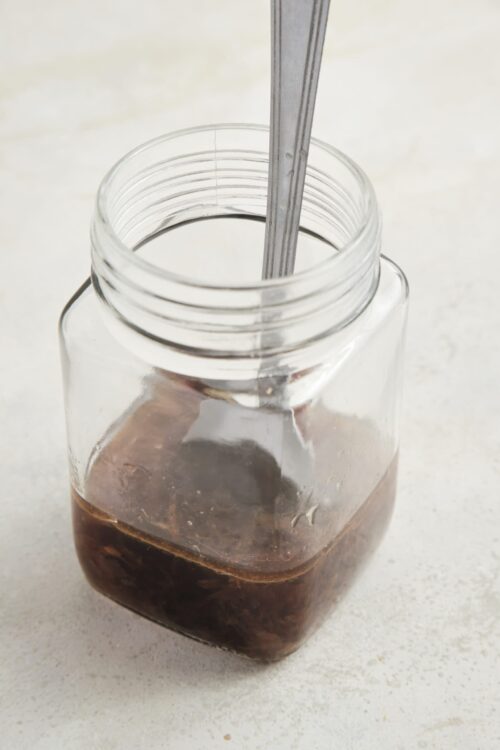 Sweetened iced coffee in a glass jar, close-up shot with a metal straw.