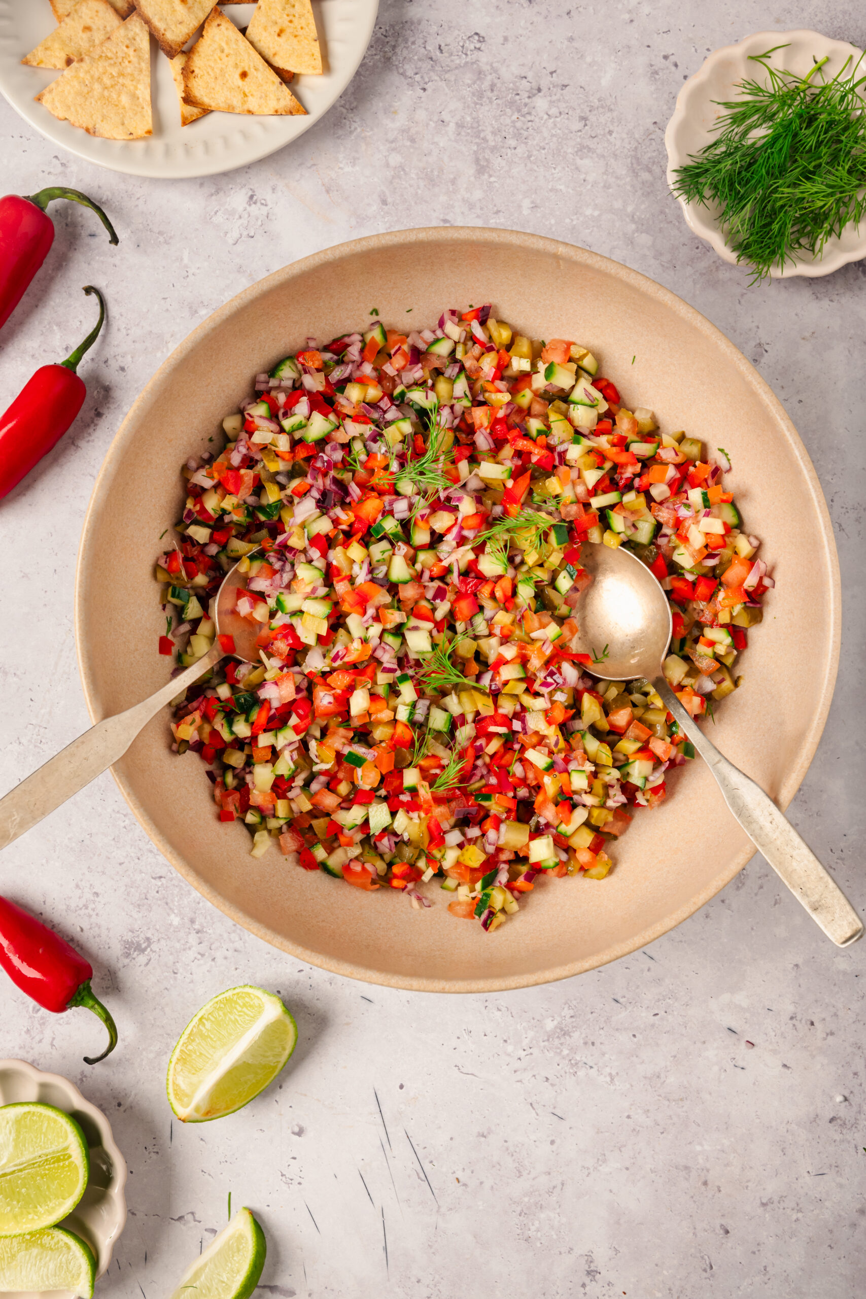 Pickle de Gallo in a bowl show from above with peppers, dill and lime wedges